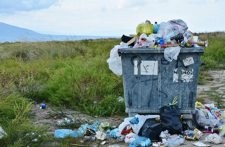 Garbage pail and pile of garbage in a field