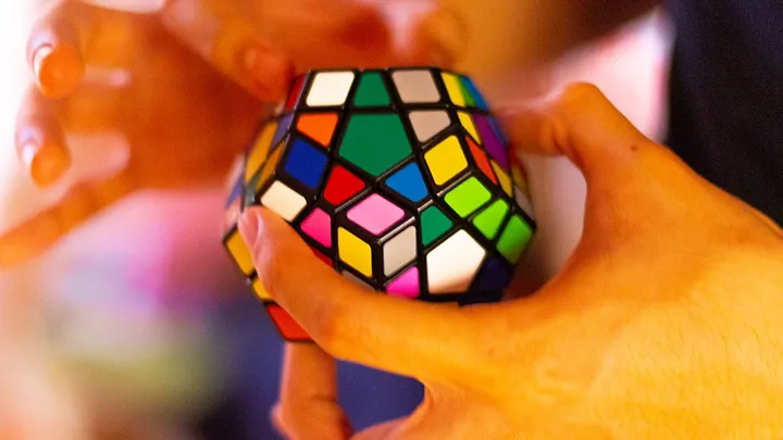 Hands solving a multisided rubiks cube puzzle