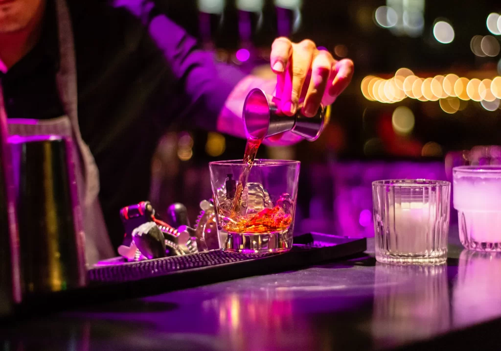 Photo of dark bar with bartender hand pouring a drink