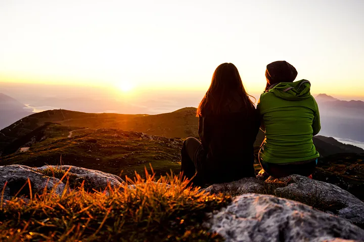 Two women overlooking a valley at sunset