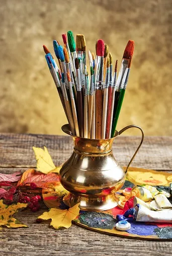 Paintbrushes in a gold pitcher