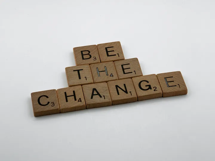 Scrabble letter tiles spelling "be the change."