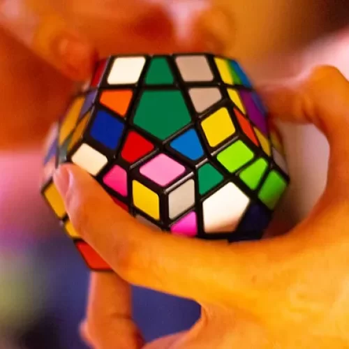 Hands solving a multisided rubiks cube puzzle