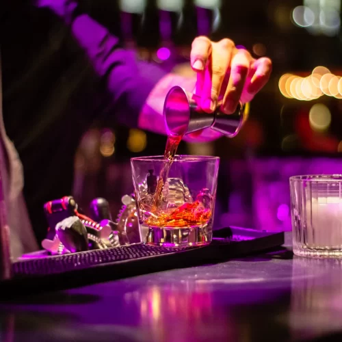 Photo of dark bar with bartender hand pouring a drink