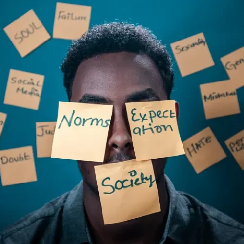 Man with post-its on his face reading norms, expectation, and society