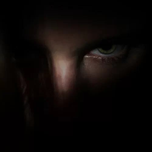 Man shrouded in the dark so you can only see his left eye.