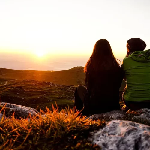 Two women overlooking a valley at sunset