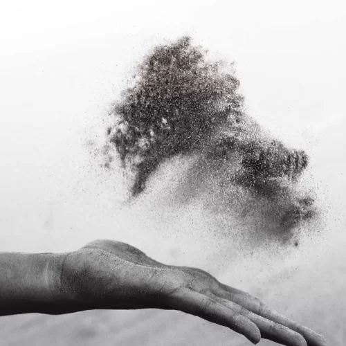 Black and white close up of a hand tossing sand.